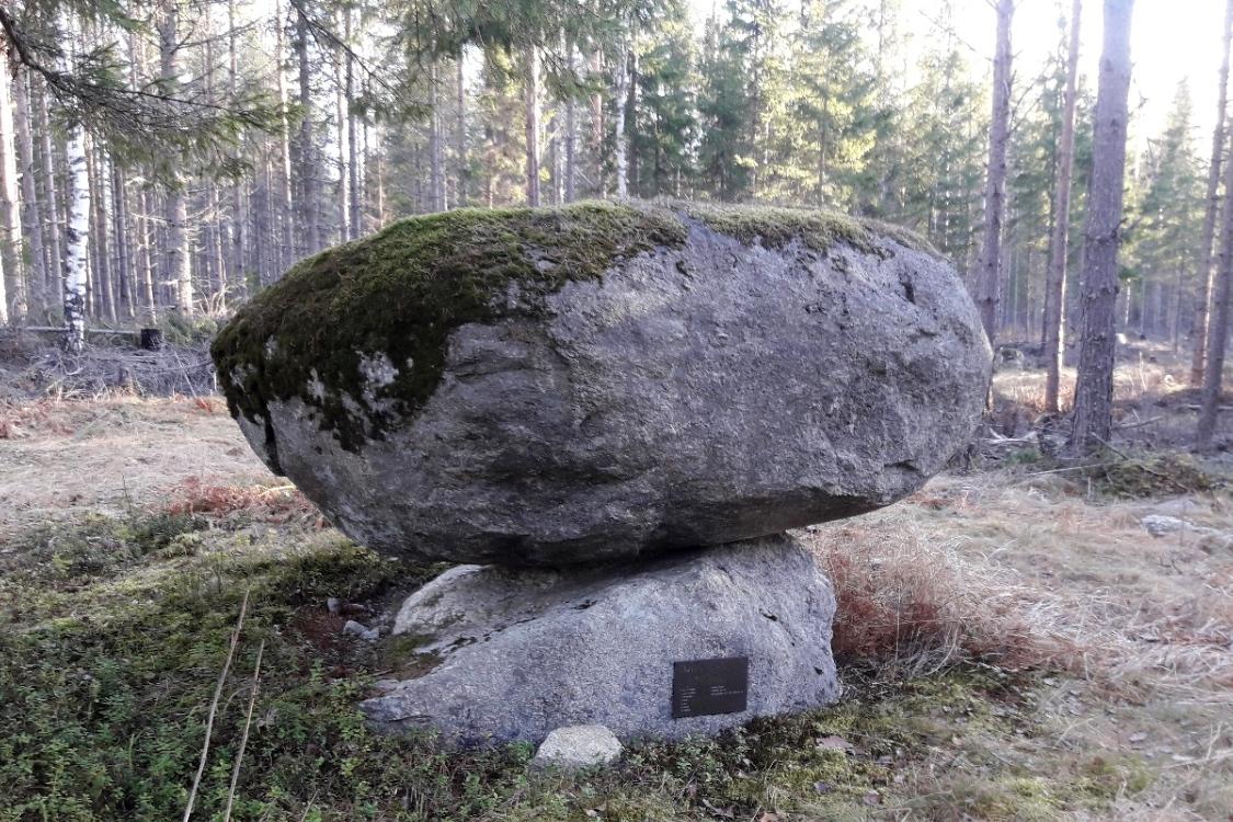 Kuvassa isompi kivi on pienemmän kiven päällä, pienemmässä kivessä kuparinen laatta.