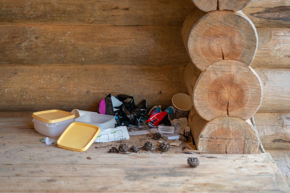 Garbage and lunchboxes have accumulated in the corner of the lean-to shelter.