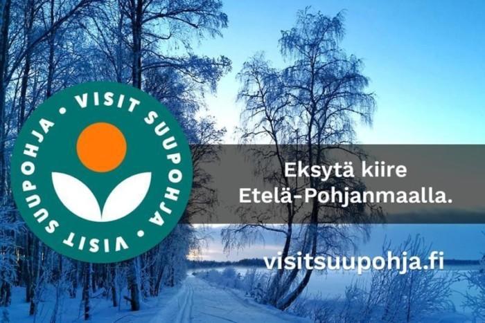 Hiihtolatu, lumihunnussa olevia koivuja ja lumipeitteinen pelto.