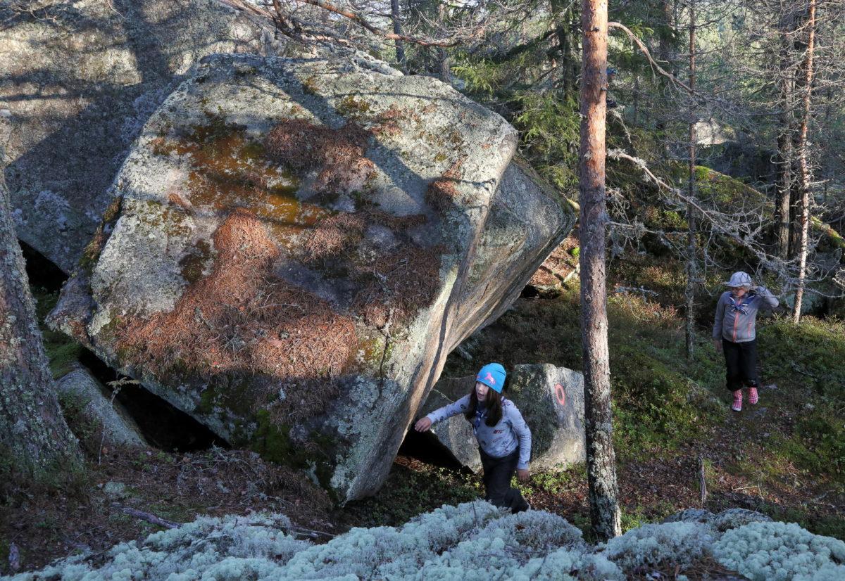 Kaksi lasta kiipeävät Kakkorin kivikkoisessa maastossa.